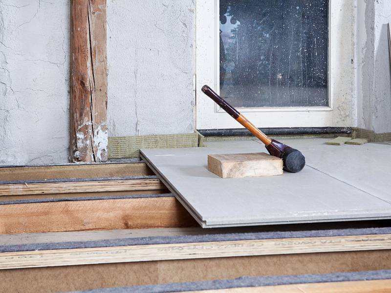 Hammer und Schlagklotz liegen auf einer GIFAfloor PRESTO Platte, die gerade auf einer nivellierten Holzbalkendecke verlegt wurde.