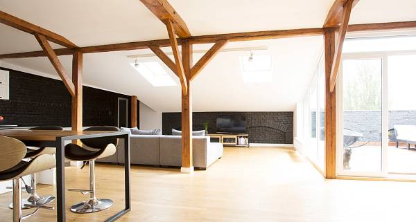 Modern eingerichtetes Loft im Altbau mit freigelegten Stützbalken als Designelemente.